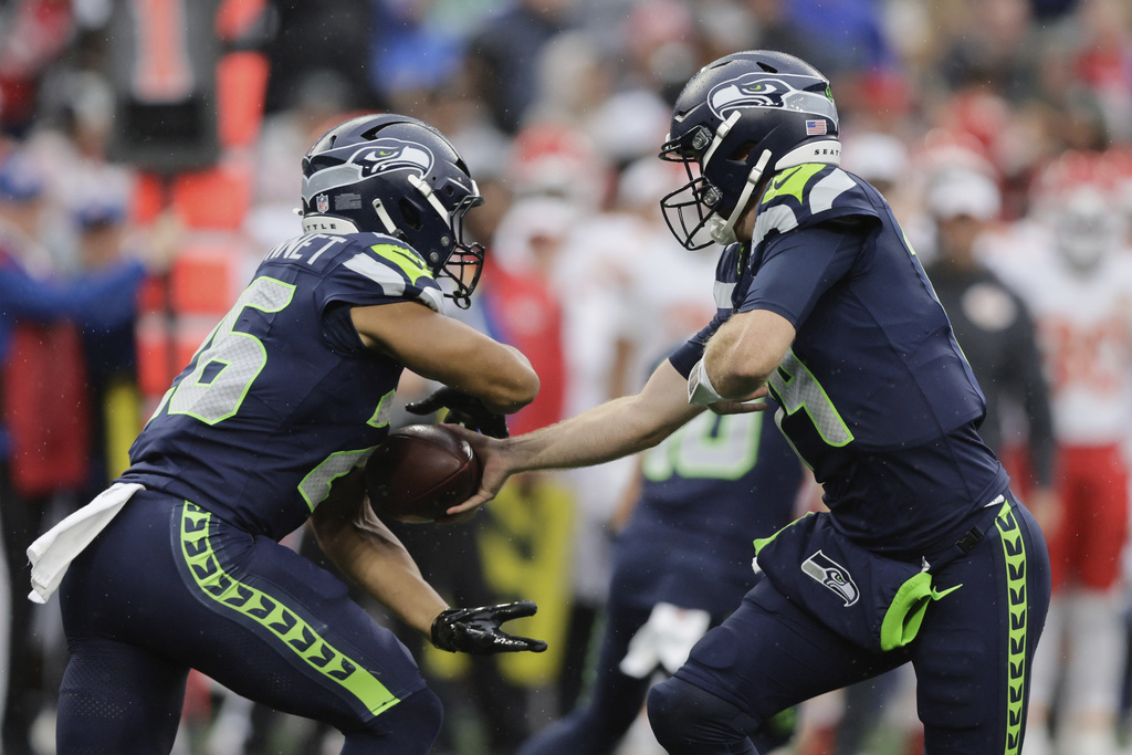 Seattle Seahawks quarterback Sam Darnold (14) passes the ball to Seattle Seahawks running back Zach Charbonnet (26) during the first half of an NFL preseason football game against the Kansas City Chiefs, Friday, Aug. 15, 2025, in Seattle. (AP Photo/John Froschauer)