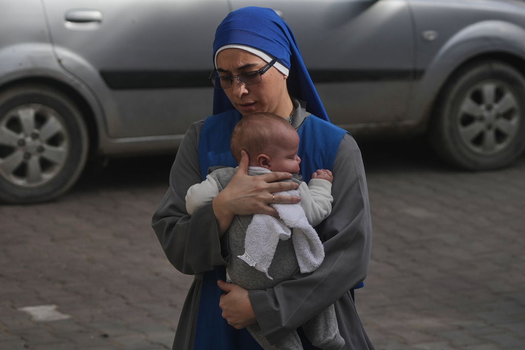 A nun holds a baby as she walks to attend Christmas Eve Mass at the Holy Family Catholic Church in Gaza City, Sunday, Dec. 21, 2025. (AP Photo/Jehad Alshrafi)