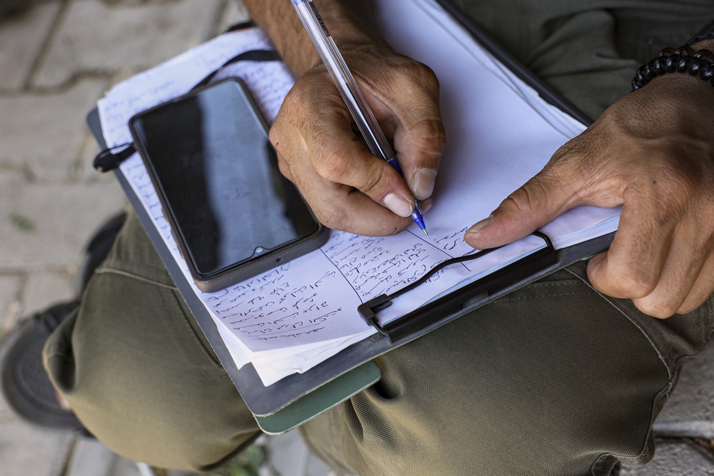 A Kurdish man signs up to join the Syrian government's General Security forces at a police station in Afrin, Syria, an area in the country's north from which Kurds were forcibly displaced years ago, Thursday Aug. 21, 2025. (AP Photo/Omar Albam)