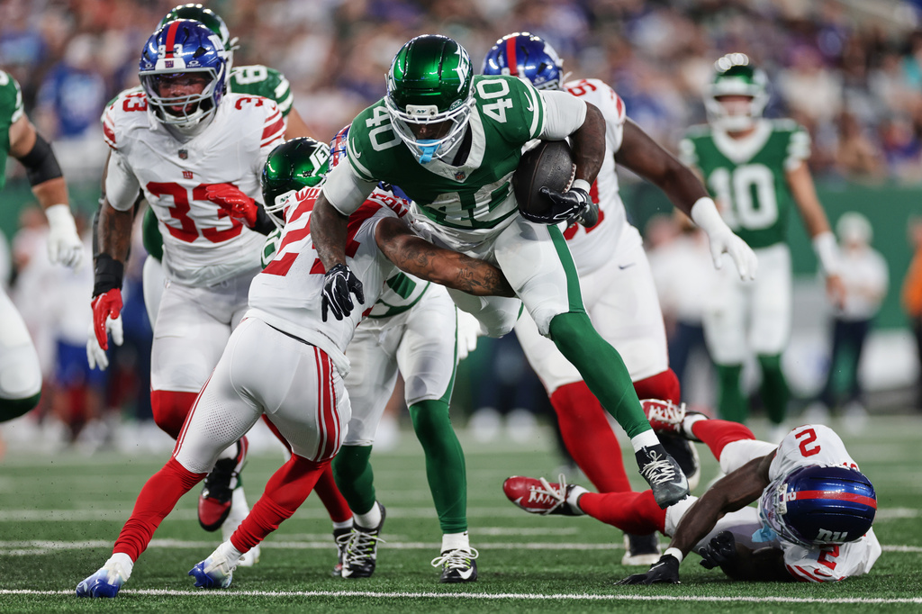 New York Jets running back Chip Trayanum (40) is tackled by New York Giants defensive back Ar'Darius Washington (24) during the first half of a preseason NFL football game, Friday, Aug. 28, 2026, in East Rutherford, N.J. (AP Photo/Adam Hunger)