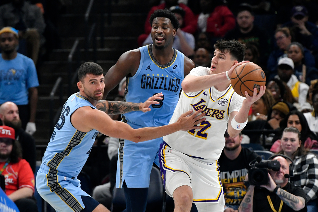 Los Angeles Lakers forward Jake LaRavia, right, handles the ball against Memphis Grizzlies guard John Konchar, left, and forward Jaren Jackson Jr., center, in the first half of an NBA Cup basketball game Friday, Oct. 31, 2025, in Memphis, Tenn. (AP Photo/Brandon Dill)