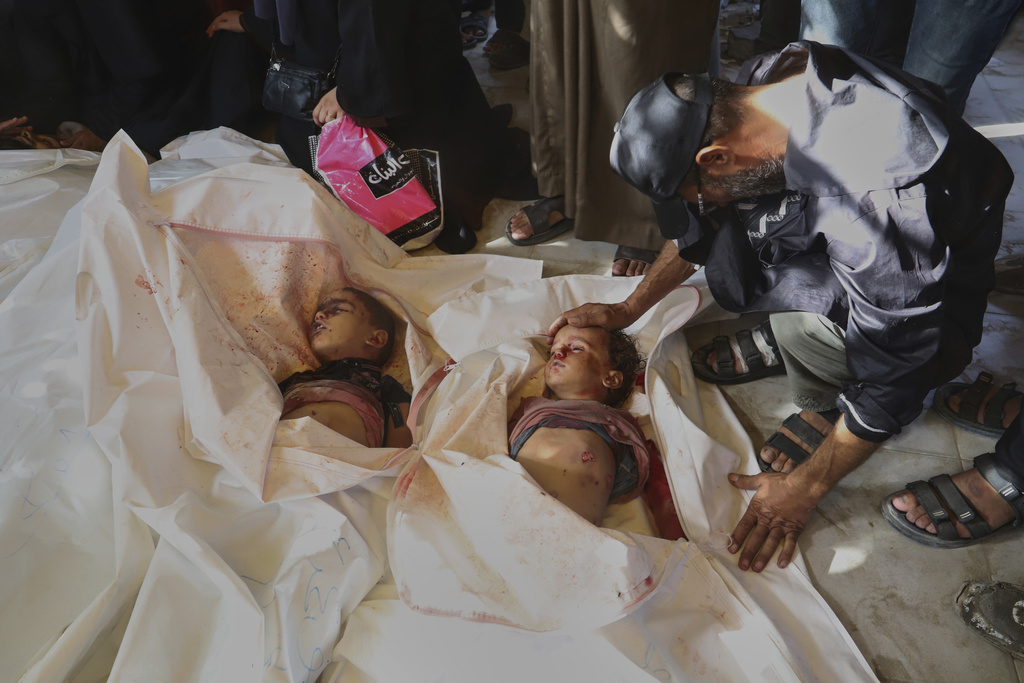 FILE - EDS NOTE: GRAPHIC CONTENT - Majed al-Mashwakhi mourns over the bodies of his grandchildren, Yusuf Eid, 4, left, and Saif Eid, 2, right, who were killed in an Israeli airstrike, during their funeral at Nasser Hospital in Khan Younis, in the southern Gaza Strip, Tuesday, Aug. 19, 2025. (AP Photo/Mariam Dagga, File)