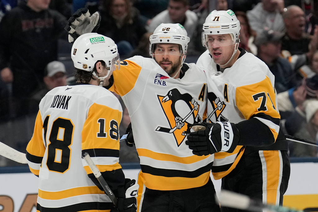 Pittsburgh Penguins center Tommy Novak (18), defenseman Kris Letang (58) and center Evgeni Malkin (71) celebrate Letang's overtime goal during an NHL hockey game against the Columbus Blue Jackets, Friday, Nov. 28, 2025, in Columbus, Ohio. (AP Photo/Carolyn Kaster)