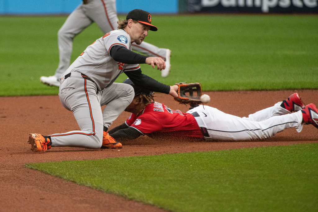 Baltimore Orioles' Gunnar Henderson, left, is late with his tag as Cleveland Guardians' Jose Ramirez is safe with a steal at second base during the first inning of a baseball game, Saturday, April 18, 2026, in Cleveland. (AP Photo/Phil Long)
