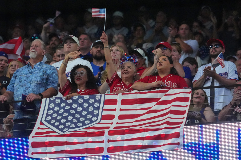 Fans stand for the national anthem before a baseball game between the Detroit Tigers and Texas Rangers, Saturday, July 4, 2026, in Arlington, Texas. (AP Photo/LM Otero)