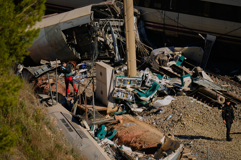 Guardia Civil officers collect evidence next to the wreckage of train cars involved in a collision in Adamuz, southern Spain, Tuesday, Jan. 20, 2026. (AP Photo/Manu Fernandez)