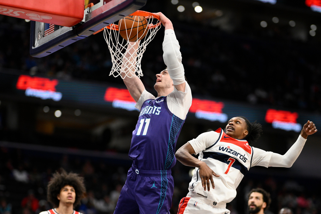 Charlotte Hornets center Ryan Kalkbrenner (11) dunks past Washington Wizards guard Bub Carrington (7) during the first half of an NBA basketball game, Sunday, Feb. 22, 2026, in Washington. (AP Photo/Nick Wass)