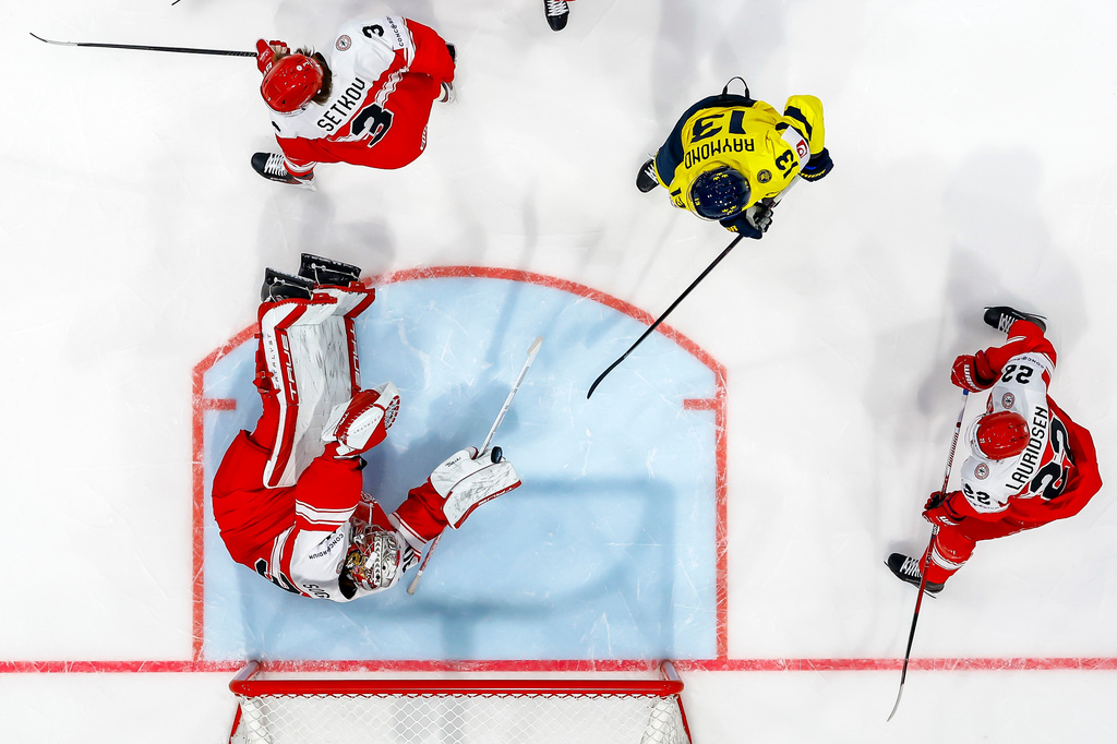 Denmark's goaltender Mads Sogaard saves a puck past Denmark's Malte Setkov #3, Sweden's Lucas Raymond, #13, and Denmark's Markus Lauridsen, #22, during the 2026 IIHF Men's Ice Hockey World Championship preliminary round group B game between Denmark and Sweden, in Fribourg, Switzerland, Sunday, May 17, 2026. (Salvatore Di Nolfi/Keystone via AP)