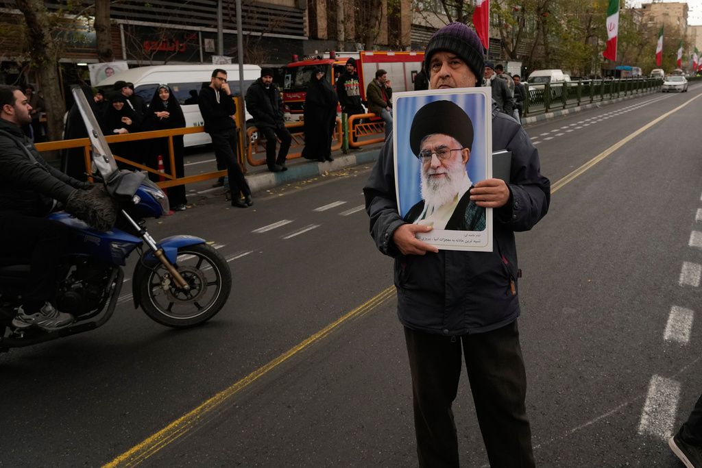 A man holds a poster of the Iranian Supreme Leader Ayatollah Ali Khamenei during a funeral ceremony for a group of security forces, who were killed during anti-government protests, in Tehran, Iran, Wednesday, Jan. 14, 2026. (AP Photo/Vahid Salemi)