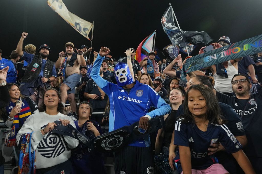 San Diego FC forward Amahl Pellegrino, center, wears a Mexican wrestling mask as he celebrates with fans after San Diego FC defeated the Portland Timbers 4-0 in Game 3 in the first round of MLS soccer's Western Conference playoffs Sunday, Nov. 9, 2025, in San Diego. (AP Photo/Gregory Bull)