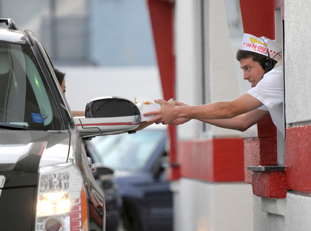 FILE - A customer receives her burger and fries from the drive-thru at In-N-Out Burger on Friday, June 11, 2010, in the Hollywood area of Los Angeles. (AP Photo/Adam Lau, File)