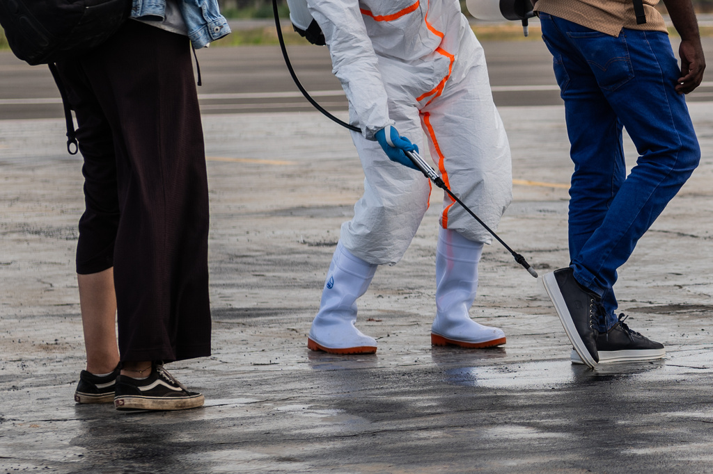 A health worker disinfects passengers prior to their boarding of the World Food Programme's (WFP) aircraft following the government's announcement of Bunia National Airport's reopening in Bunia, Congo, Tuesday, June 2, 2026. (AP Photo/Moses Sawasawa)