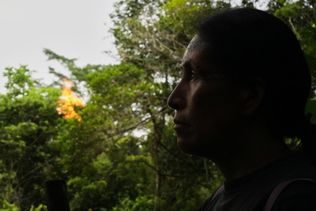 Salomé Aranda walks as a gas flare burns in the background in Sucumbios, Ecuador, Friday, March 6, 2026. (AP Photo/Dolores Ochoa)