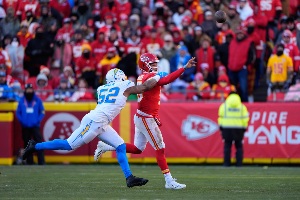 Kansas City Chiefs quarterback Patrick Mahomes, right, throws the ball away under pressure from Los Angeles Chargers outside linebacker Khalil Mack (52) during the second half of an NFL football game Sunday, Dec. 14, 2025, in Kansas City, Mo. (AP Photo/Charlie Riedel)