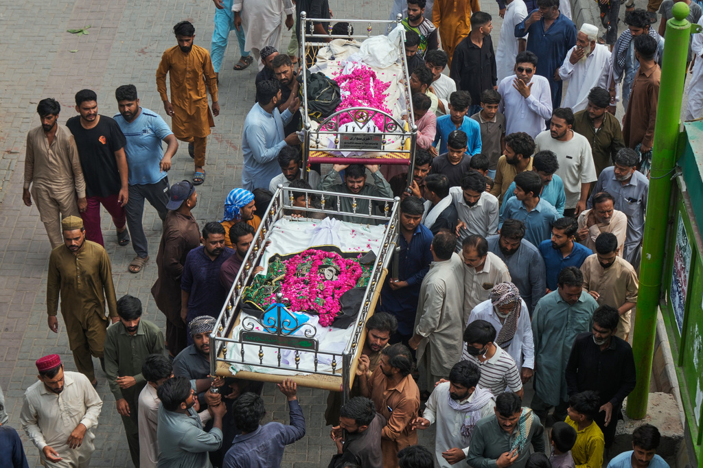 People carry the bodies of children, who were killed in a roof collapse at a tutoring center on the outskirts of Lahore, Pakistan after a funeral prayer Wednesday, July 1, 2026. (AP Photo/K.M. Chaudary)