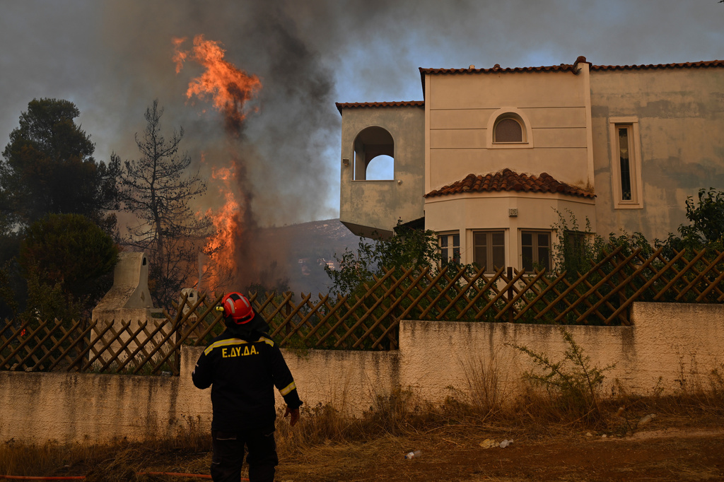 A volunteer firefighter observs a flame rising next to a house during a wildfire near Porto Germeno, northwest of Athens, Greece, Sunday, Aug. 2, 2026. (AP Photo/Michael Varaklas)