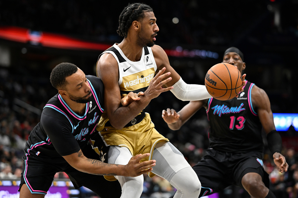 Washington Wizards center Alex Sarr, attempts to escape the defense of Miami Heat guard Terry Rozier, left, and Heat center Bam Adebayo (13) during the first half of an NBA basketball game, Sunday, Feb. 8, 2026, in Washington. (AP Photo/John McDonnell)
