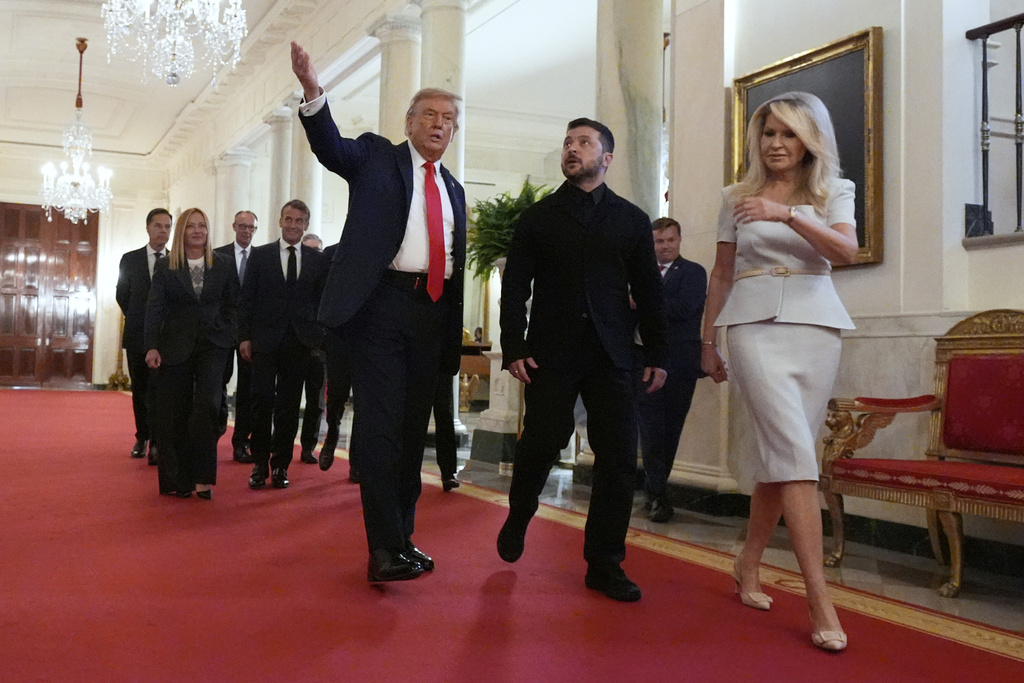 Monica Crowley, White House chief of protocol, from right, Ukrainian President Volodymyr Zelenskyy, President Donald Trump, France's President Emmanuel Macron, Germany's Chancellor Friedrich Merz, Italy's Prime Minister Giorgia Meloni and NATO Secretary General Mark Rutte walk through the Cross Hall of the White House, Monday, Aug. 18, 2025, in Washington. (AP Photo/Alex Brandon)