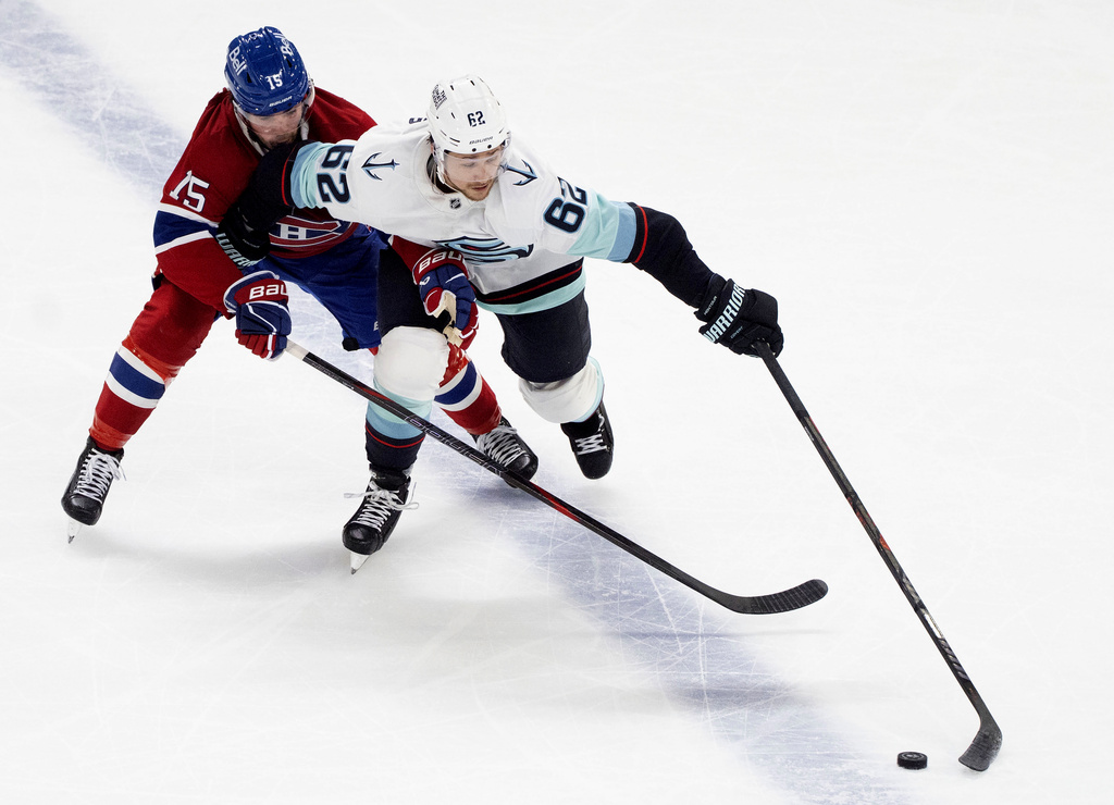 Montreal Canadiens' Alex Newhook (15) and Seattle Kraken's Brandon Montour (62) battle for the puck during second period NHL hockey action in Montreal on Tuesday, Oct. 14, 2025. (Christinne Muschi/The Canadian Press via AP)