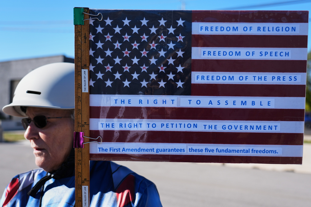 Jeanette Mancusi holds a American flag with writing outside an ICE processing facility in the Chicago suburb of Broadview, Ill., Monday, Oct. 20, 2025. (AP Photo/Nam Y. Huh)