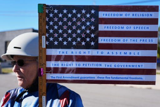 Jeanette Mancusi holds a American flag with writing outside an ICE processing facility in the Chicago suburb of Broadview, Ill., Monday, Oct. 20, 2025. (AP Photo/Nam Y. Huh) Jeanette Mancusi holds a American flag with writing outside an ICE processing facility in the Chicago suburb of Broadview, Ill., Monday, Oct. 20, 2025. (AP Photo/Nam Y. Huh)