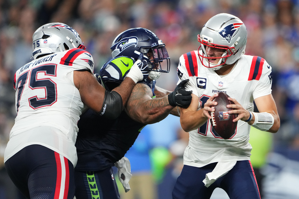 Seattle Seahawks nose tackle Byron Murphy II, center, pressures New England Patriots quarterback Drake Maye, right, as New England Patriots guard Alijah Vera-Tucker, right, moves in during the second half of an NFL football game, Wednesday, Sept. 9, 2026, in Seattle. (AP Photo/Lindsey Wasson)