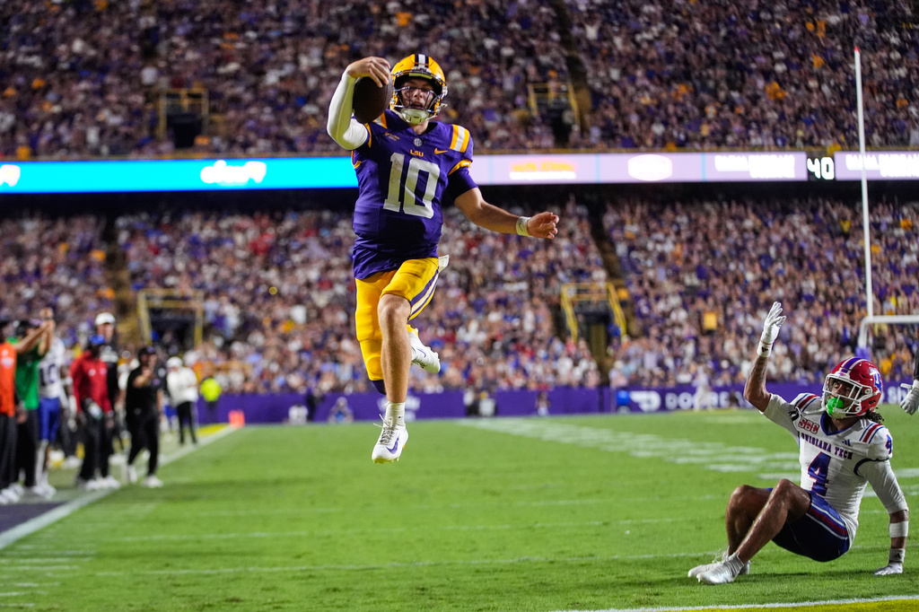 LSU quarterback Sam Leavitt (10) leaps in the air past Louisiana Tech safety Kam Franklin (4) as he scores a touchdown in the second half of an NCAA college football game, Saturday, Sept. 12, 2026 in Baton Rouge, La. (AP Photo/Gerald Herbert)