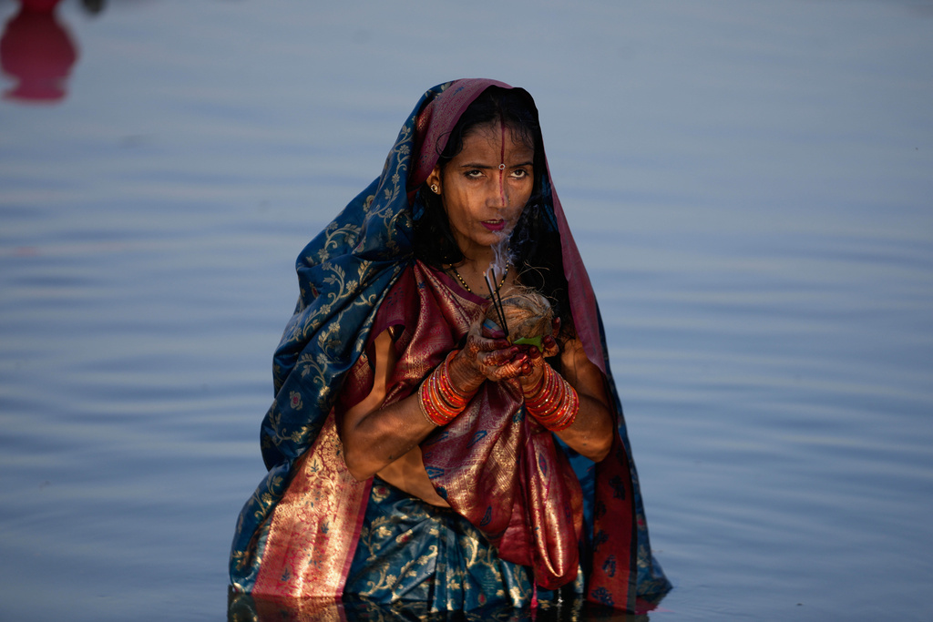 A Hindu devotee performs rituals at sunset on the banks of the Tawi River during Chhath Puja festival in Jammu, India, Monday, Oct. 27, 2025. (AP Photo/Channi Anand)