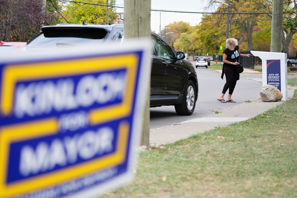 A sign for Detroit mayoral candidate Solomon Kinloch is displayed as a voter drops off their ballot at a drop box in Detroit, Tuesday, Nov. 4, 2025. (AP Photo/Ryan Sun)