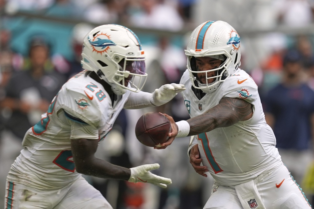 Miami Dolphins' Tua Tagovailoa hands off to De'Von Achane during the second half of an NFL football game against the New England Patriots Sunday, Sept. 14, 2025, in Miami Gardens, Fla. (AP Photo/Rebecca Blackwell)