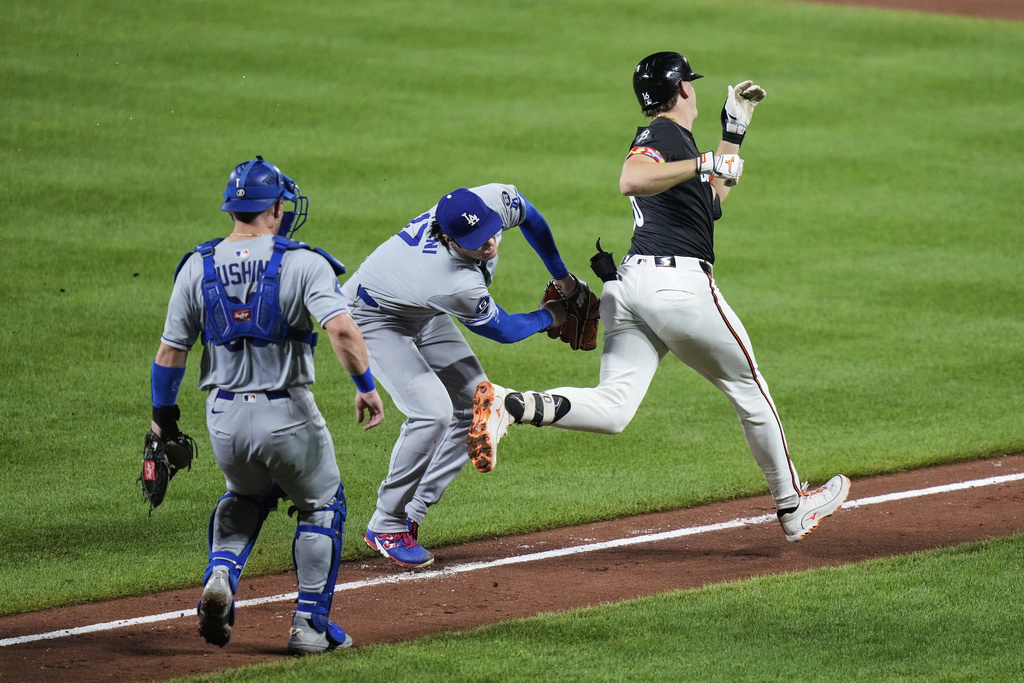 Los Angeles Dodgers starting pitcher Shohei Ohtani, center, tags out Baltimore Orioles' Coby Mayo, right, during the third inning of a baseball game, Friday, Sept. 5, 2025, in Baltimore. (AP Photo/Stephanie Scarbrough)