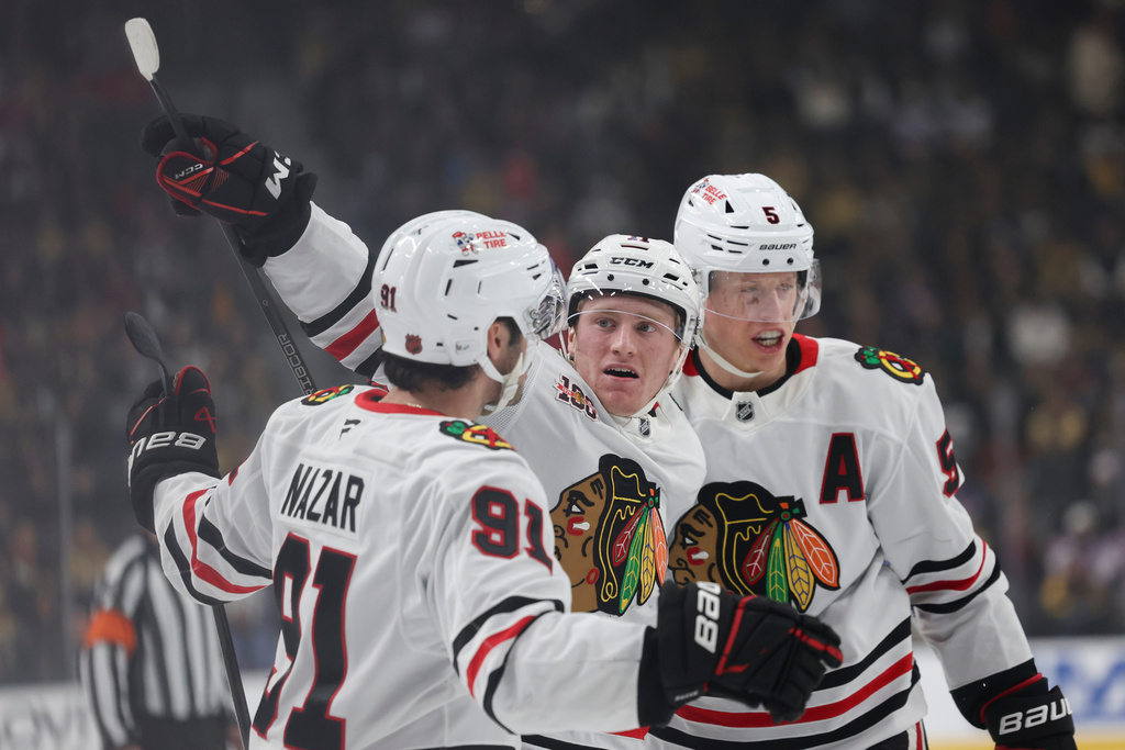 Chicago Blackhawks centers Frank Nazar (91) and Oliver Moore (11) celebrate with defenseman Connor Murphy (5) after Moore's goal against the Vegas Golden Knights during the first period of an NHL hockey game Tuesday, Dec. 2, 2025, in Las Vegas. (AP Photo/Ian Maule)