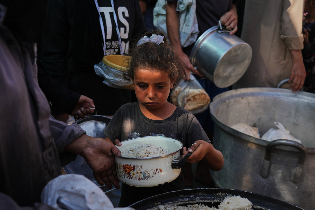 Palestinians receive donated food at a community kitchen in Deir al-Balah, central Gaza Strip, Thursday, Oct. 16, 2025. (AP Photo/Abdel Kareem Hana)