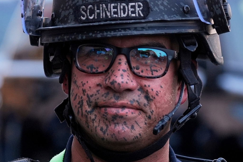 A police officer's face is covered in pepper spray outside the Metropolitan Detention Center of downtown Los Angeles, Sunday, June 8, 2025, following an immigration raid protest the night before. (AP Photo/Jae Hong, File)