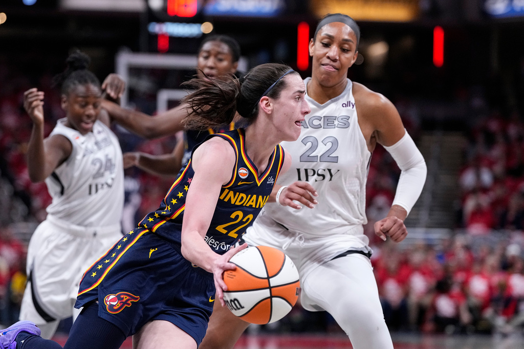 Indiana Fever guard Caitlin Clark (22), center, drives on Las Vegas Aces center A'ja Wilson (22) during the first half in Game 2 of a WNBA basketball first-round playoff series in Indianapolis, Tuesday, Sept. 29, 2026. (AP Photo/Michael Conroy)