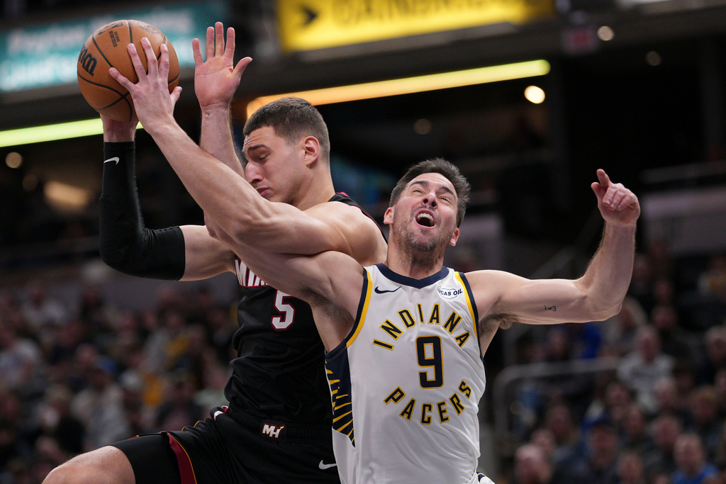 Indiana Pacers guard T.J. McConnell (9) locks arms with Miami Heat forward Nikola Jovic (5) while going for a rebound during the first half of an NBA basketball game in Indianapolis, Saturday, Jan. 10, 2026. (AP Photo/AJ Mast)