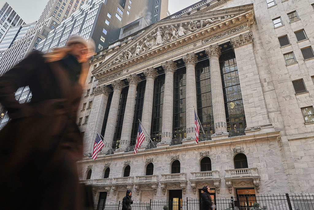 Morning commuters pass the New York Stock Exchange, Tuesday, Jan. 20, 2026. (AP Photo/Richard Drew)
