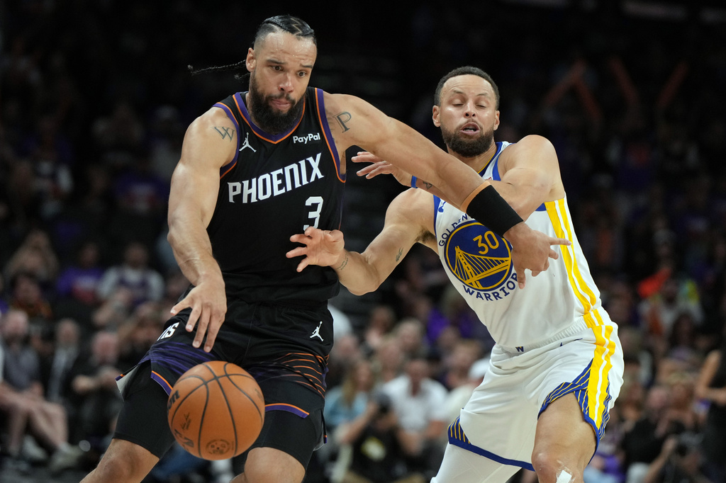 Phoenix Suns forward Dillon Brooks drives past Golden State Warriors guard Stephen Curry (30) during the second half of an NBA basketball play-in tournament game, Friday, April 17, 2026, in Phoenix. (AP Photo/Rick Scuteri)