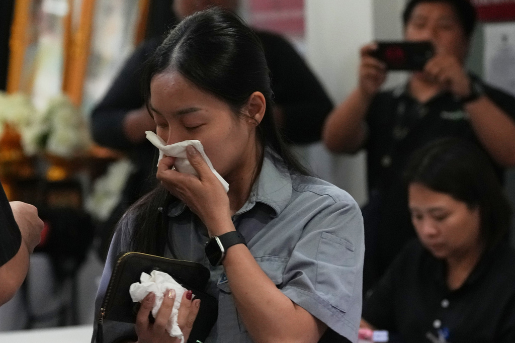 One of relatives of fire victims, front, leaves the Institute of Forensic Police hospital in Bangkok, Thailand, Monday, July 13, 2026, following a fire at a beer hall. (AP Photo/Sakchai Lalit)