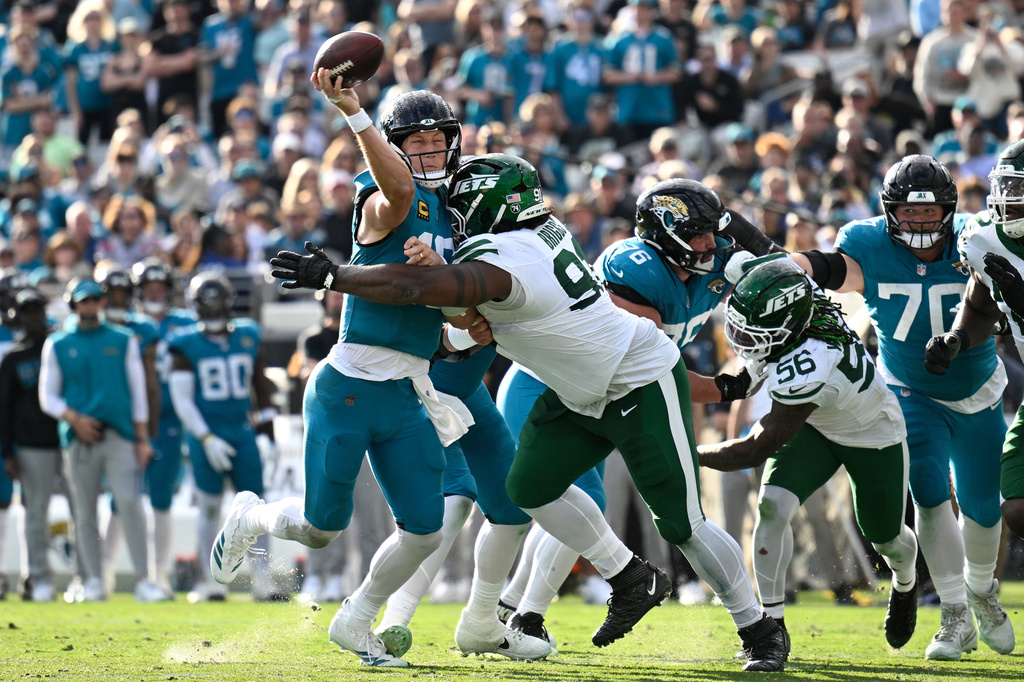 Jacksonville Jaguars quarterback Trevor Lawrence, center left, throws a pass against New York Jets defensive tackle Jowon Briggs, center right, during the second half of an NFL football game, Sunday, Dec. 14, 2025, in Jacksonville, Fla. (AP Photo/Phelan M. Ebenhack)