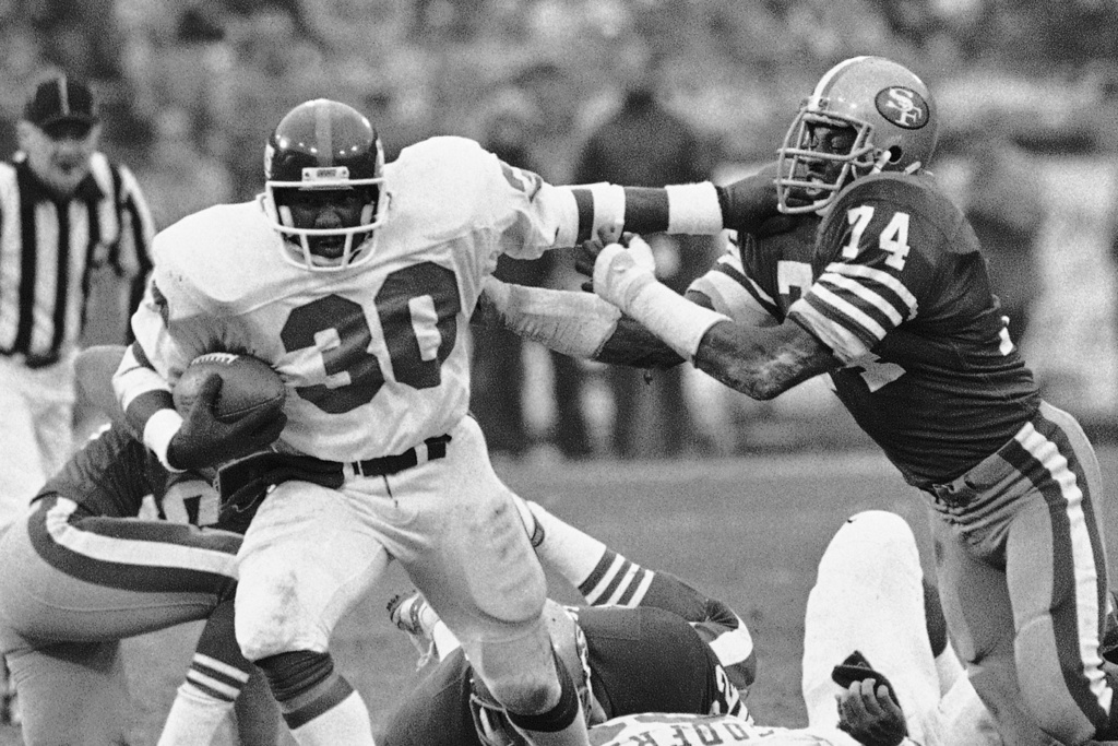 FILE - San Francisco 49ers defensive end Fred Dean (74) gets a hand on New York Giants running back Tony Galbreath (30) during the fourth quarter of an NFL football playoff game at Candlestick Park, Dec. 31, 1984 in San Francisco. (AP Photo/File)