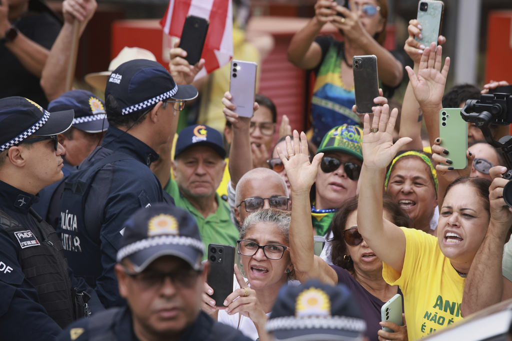 Supporters cheer as former President Jair Bolsonaro, temporarily allowed out of house arrest for medical treatment, departs a hospital in Brasilia, Brazil, Sunday, Sep. 14, 2025. (AP Photo/Luis Nova)