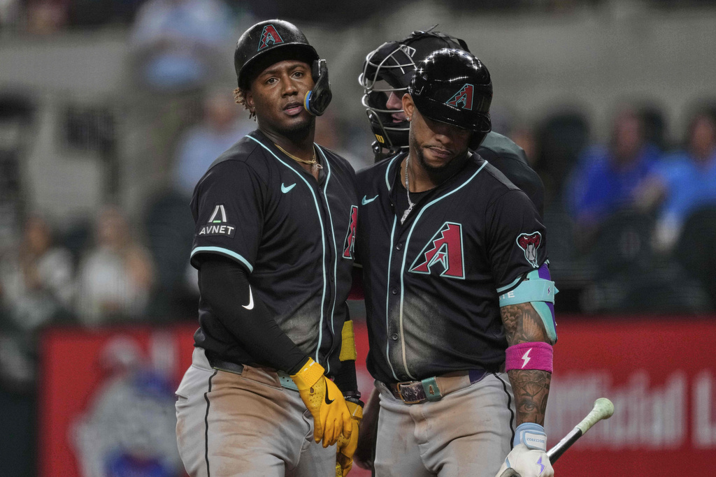 Arizona Diamondbacks' Ketel Marte, right, escorts Geraldo Perdomo away from the home plate after Perdomo began arguing with umpire Nate Tomlinson, rear, after being called out on strikes in the ninth inning of a baseball game against the Texas Rangers Tuesday, Aug. 12, 2025, in Arlington, Texas. (AP Photo/Tony Gutierrez)