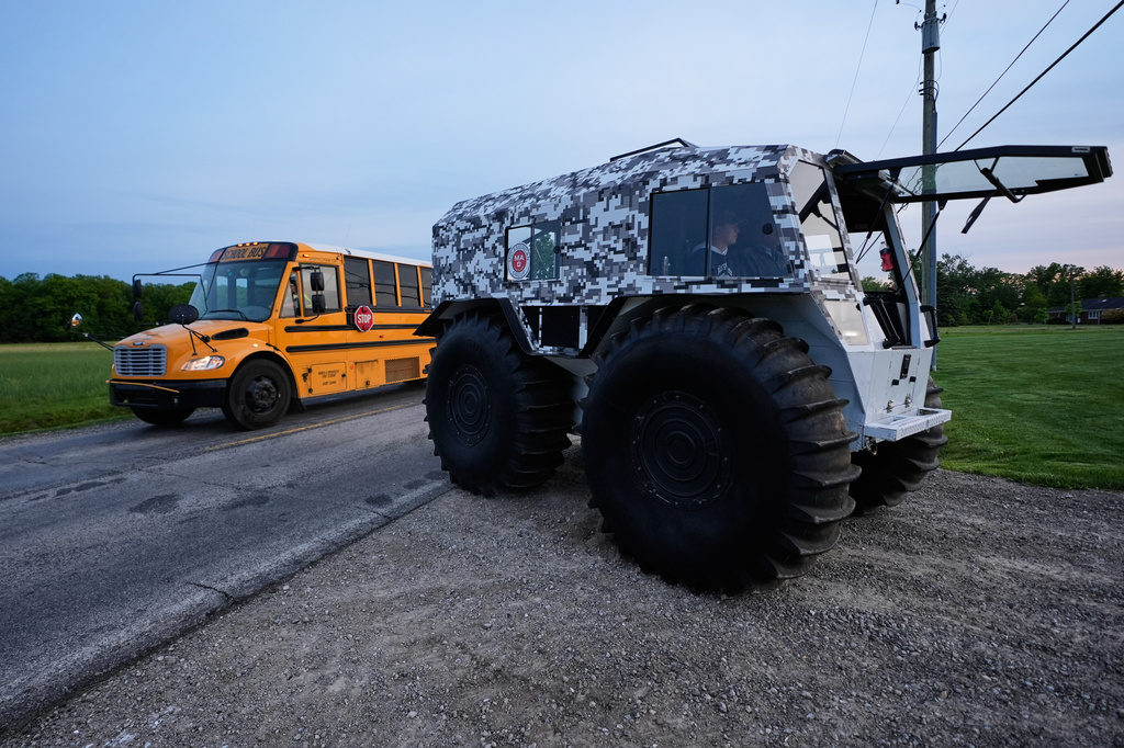 A Sherp N-1200 turns as a school bus passes during Tractor Day for graduating seniors at Airport High School Friday, May 22, 2026, in Carleton, Mich. (AP Photo/Paul Sancya)