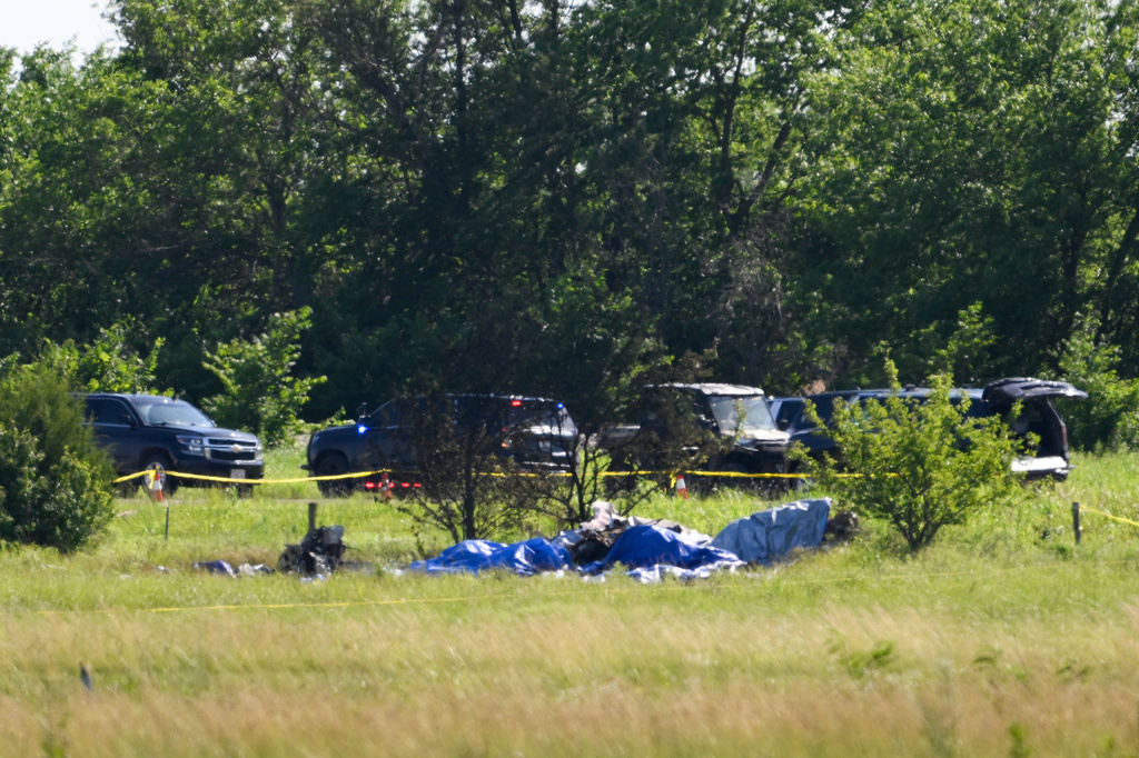 Part of the wreckage of a plane crash is covered with a blue tarp at Butler Memorial Airport in Butler, Mo., Sunday, June 14, 2026. (AP Photo/Reed Hoffmann)