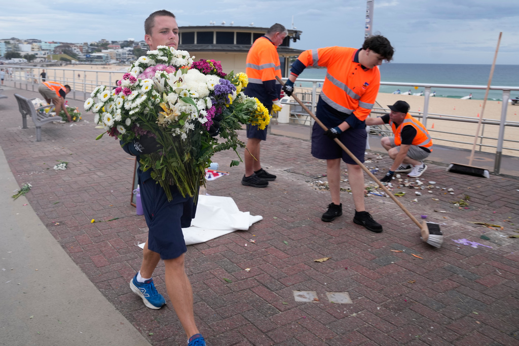 Workers gather floral tributes, messages of support and items left as a memorial is dismantled in Sydney, Monday, Dec. 22, 2025, a week after an attack on a Jewish festival that left 15 dead. (AP Photo/Rick Rycroft)