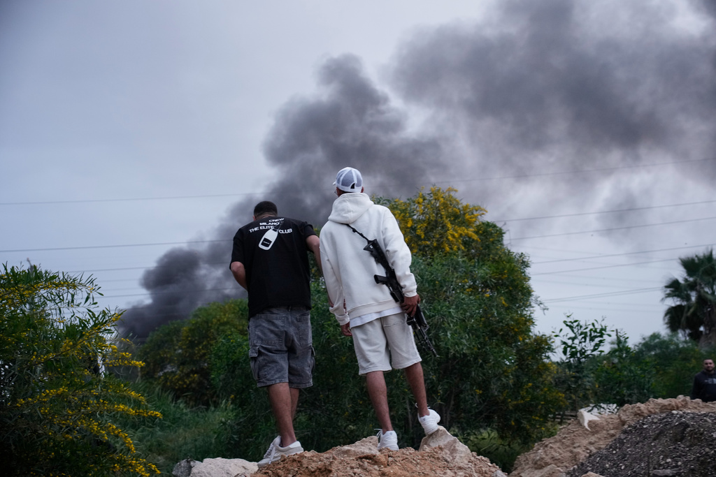 Smoke rises following a direct hit by an Iranian missile strike in Holon, central Israel, Friday, March 13, 2026. (AP Photo/Ohad Zwigenberg)