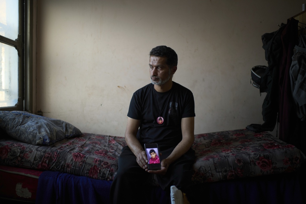 Iyad Rajab holds a phone with a photo of his 10-year-old son, Saddam Rajab, who was killed by Israeli fire, as he sits on the boy’s bed, in the West Bank city of Tulkarem, March 17, 2025. (AP Photo/Leo Correa)