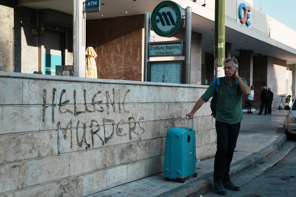 A traveler stands outside the closed main railway station during a nationwide 24-hour strike, as labor unions demand higher wages and the withdrawal of a bill that changes work hours in Athens, Greece, Wednesday, Oct. 1, 2025. (AP Photo/Thanassis Stavrakis)
