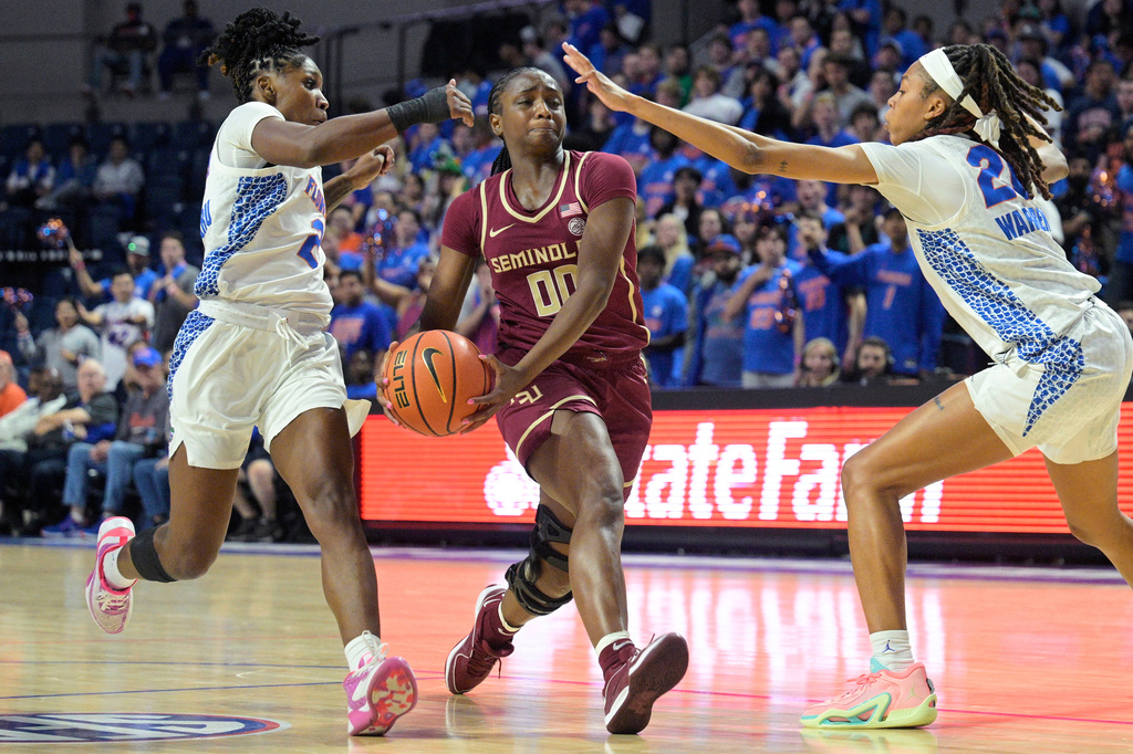 FILE - Florida State guard Ta'Niya Latson (00), who has since transferred to Soouth Carolina, drives to the basket between Florida's Aliyah Matharu (2) and Jeriah Warren (20) during the second half of an NCAA college basketball game, Friday, Nov. 17, 2023, in Gainesville, Fla. (AP Photo/Phelan M. Ebenhack, File)